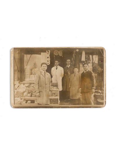 Familie în fața unei prăvălii, fotografie tip carte poștală
